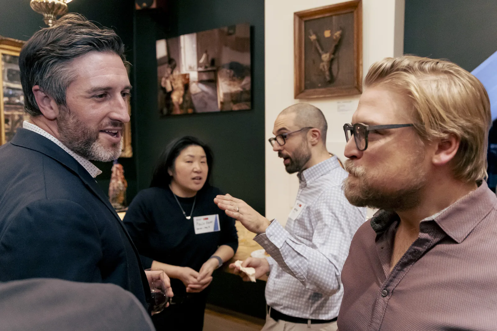 Ottawa professionals in animated conversation at a business networking event, busy room visible in the background