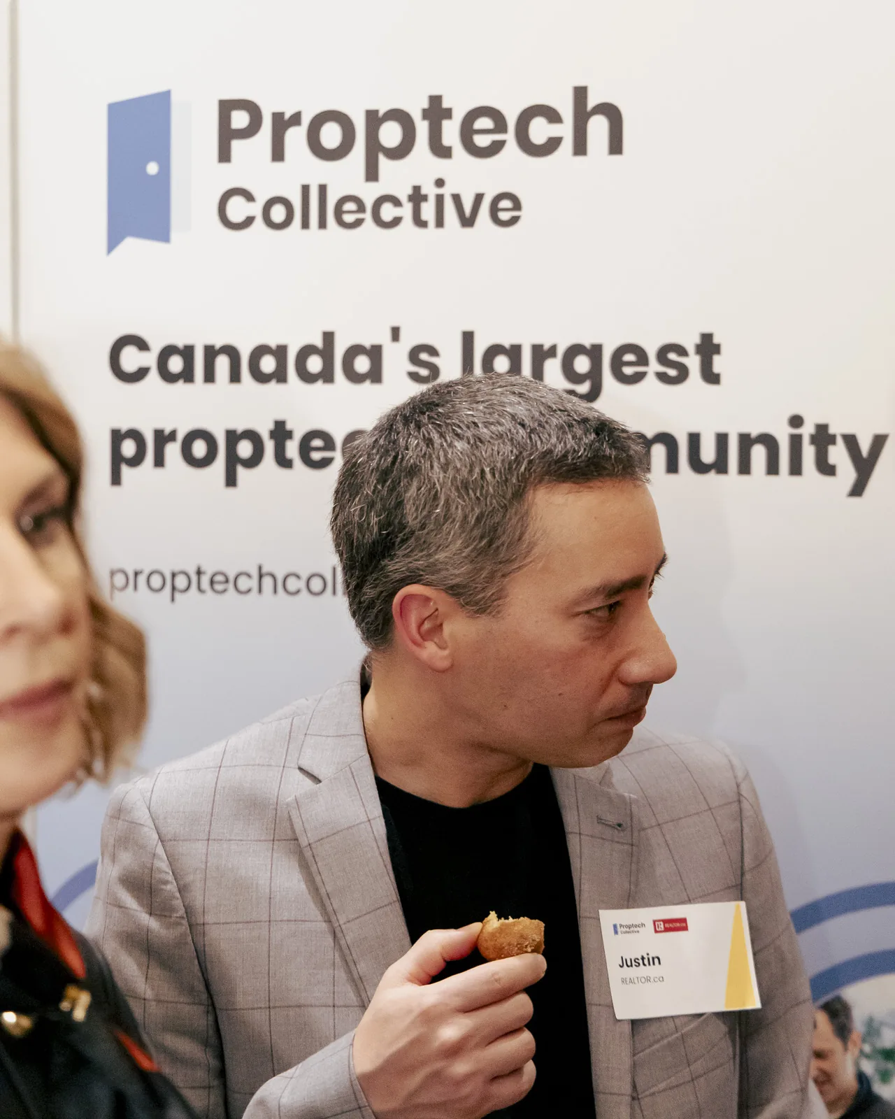 Proptech Collective Ottawa event attendee in conversation in front of the Proptech Collective Canada's largest proptech community banner